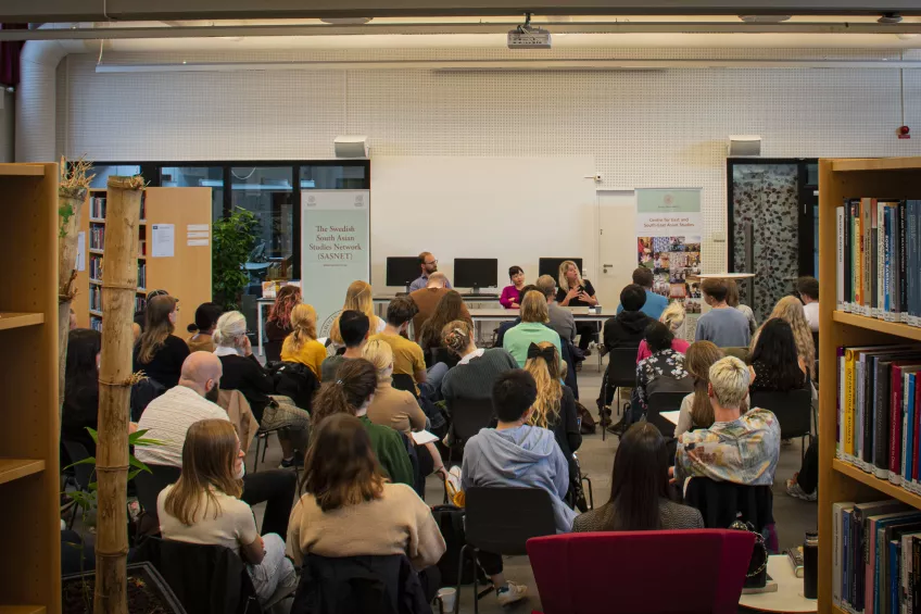 The picture shows a room full of people listening to three penallists in the Asia library at Lunds University